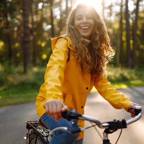 Beautiful,Happy,Woman,In,Yellow,Coat,Riding,Bicycle,In,Autumn